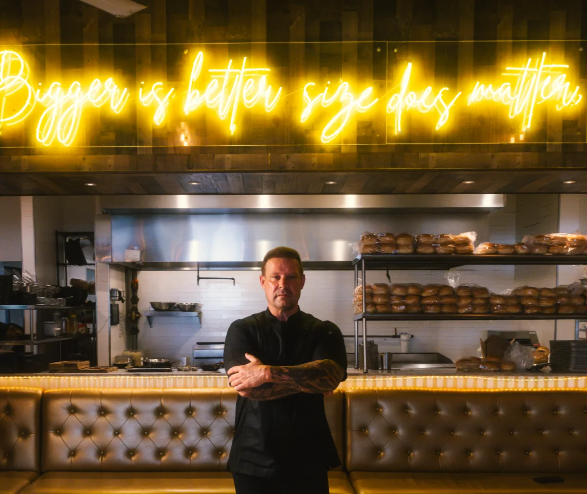 Alexander Ringleb standing in the open kitchen and dining room, under the house neon